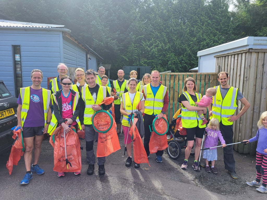 a group of about 20 volunteers in high vis vests holding litter licking equipment at the Real Food Cafe in Tyndrum 