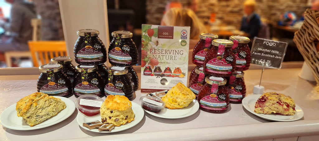 Jars of raspberry and blackcurrant heather hills farm jam large freshly made scones on plates with portions of jam and butter on the plates, Scottish produce display at the Real food cafe in Tyndrum