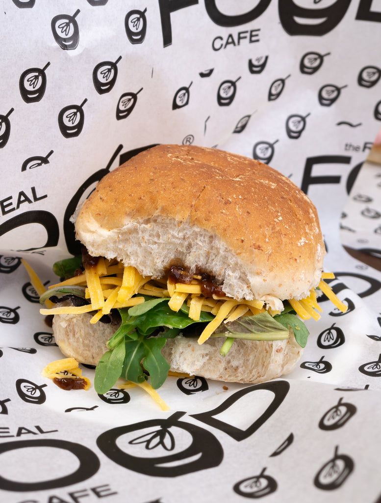brown roll with ploughman's filling - this includes an onion chutney, grated cheese and rocket. The roll is wrapped in a real food cafe grease-proof paper.